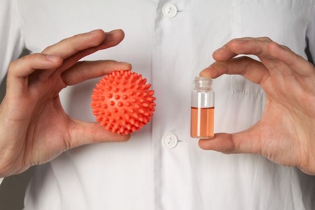 doctor holds a model of the coronavirus.