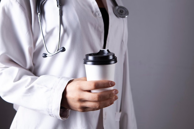 Doctor holds a paper cup of coffee in hands