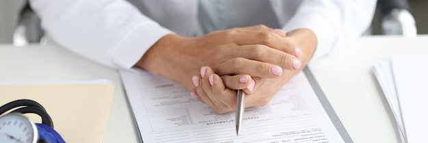 Doctor holds pen and medical record at workplace medical care and services concept