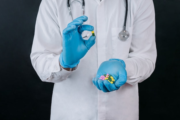 Photo the doctor holds the pills in his hands on a dark background.