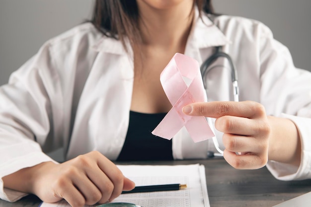 The doctor holds a pink ribbon for aids