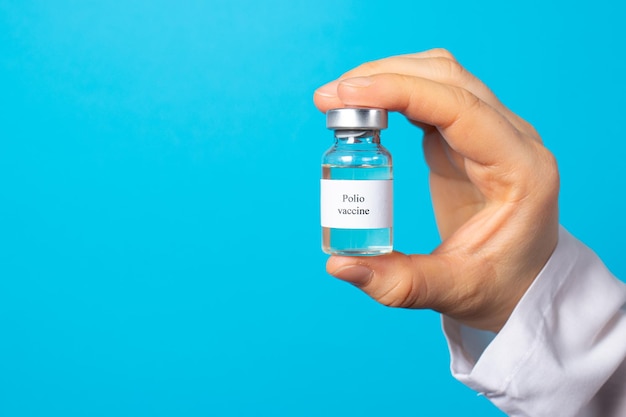 A doctor holds a polio vaccine on a blue background