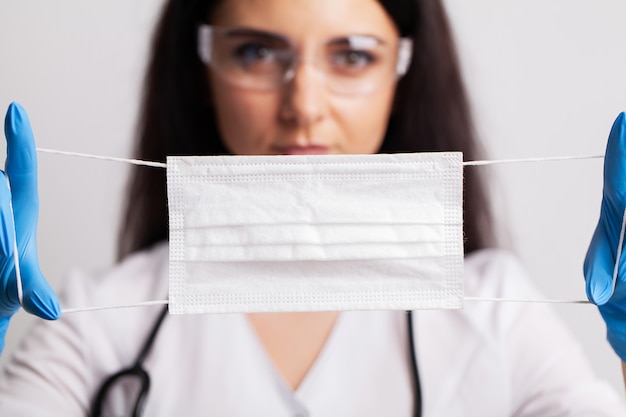 The doctor holds a protective surgical mask