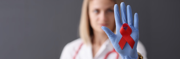 Doctor holds red ribbon in his hand health safety and love concept