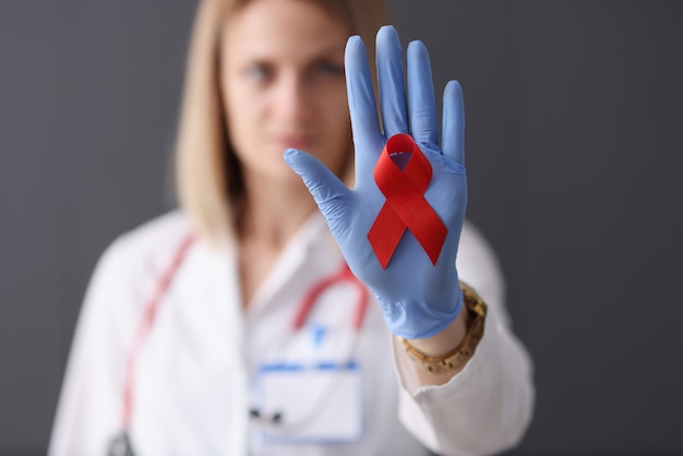 Doctor holds red ribbon in his hand health safety and love concept