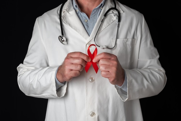 Doctor holds red ribbon with hands World AIDS Day Support from health personnel to people with hiv