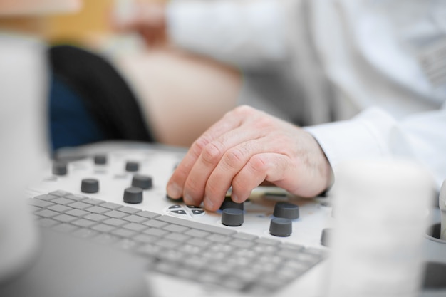 The doctor holds an ultrasound on the patient, a hand close up