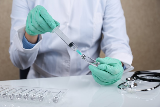 Doctor holds vial of medicine and syringe