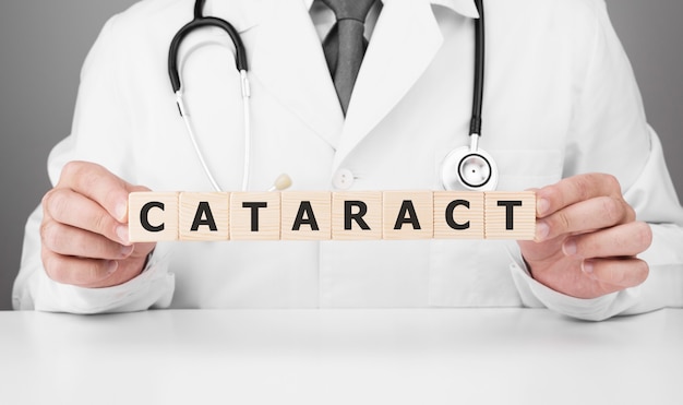 Doctor holds wooden cubes in his hands with text CATARACT