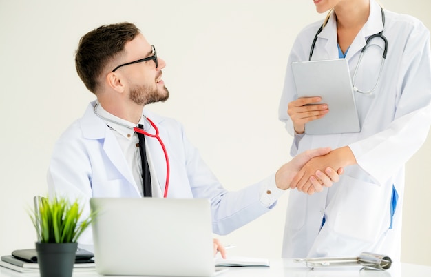 Doctor at the hospital giving handshake to another doctor showing success and teamwork.