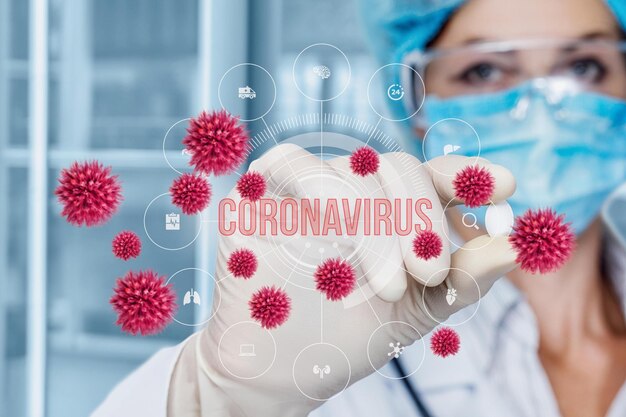 사진 실험실 코트와 장갑을 입은 의사는 화면에 코로나바이러스라는 단어가 있는 빨간색 바이러스를 보유하고 있습니다.