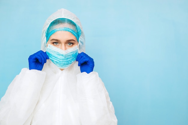 Doctor in beschermende kleding de dokter van het meisje draagt een beschermende een masker en blauwe handschoenen. epidemie corona-virus. virus portret close-up van gemaskerde arts. | Premium Foto