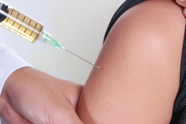 写真 医師が子供の腕と針にワクチンや抗生物質を注射しています