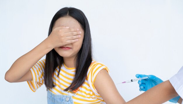 Doctor injecting vaccination in arm of young Asian girl on white background student medical concept