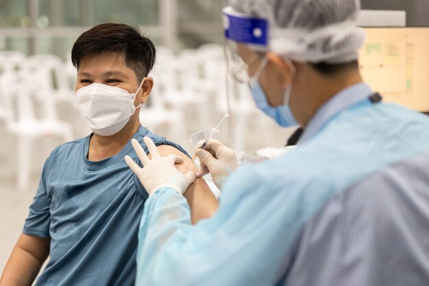 Doctor injecting vaccine to male patient against coronavirus pandemic