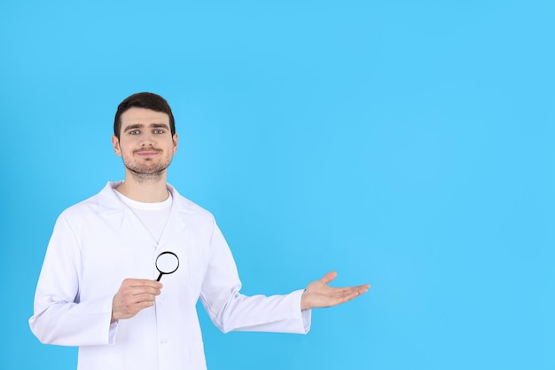 Doctor - intern with magnifier on blue background