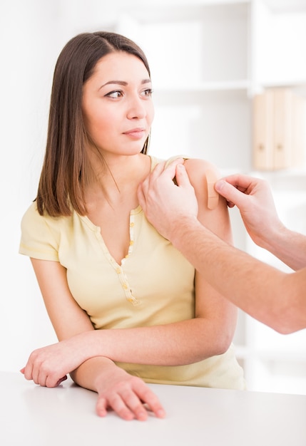 Doctor is applying an adhesive bandage to young man.