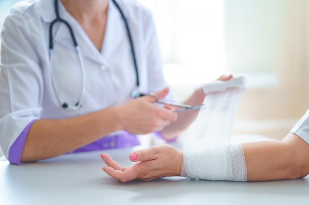 Doctor is bandaging wrist of patient in clinic