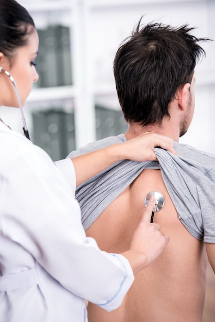 Doctor is examining the patient lungs with a stethoscope.