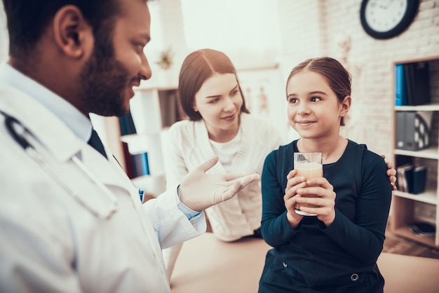 Doctor is giving pop pill and water to daughter.