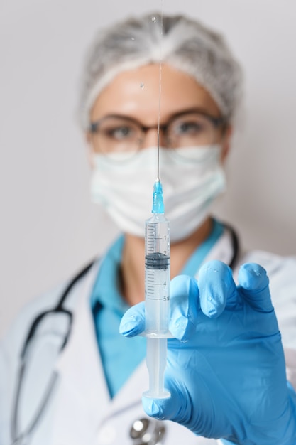 医者はワクチンや薬の入った注射器を持っている