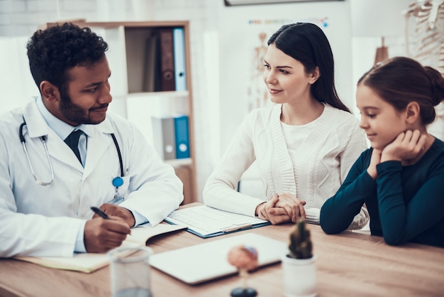 Doctor is listening to mother and daughter.