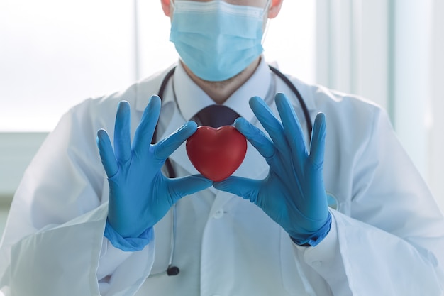 Doctor is looking at the heart in his hands