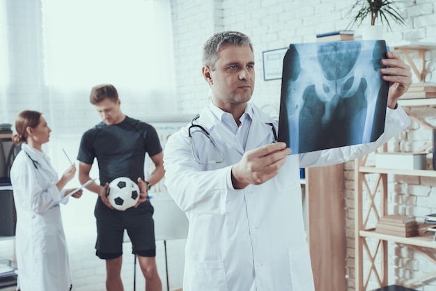 Doctor is looking at x-ray for athlete