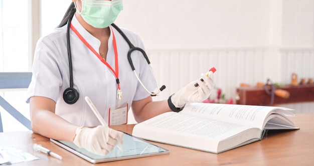 The doctor is recording the results of the blood test tube with a tablet