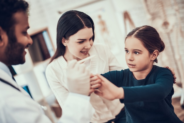 Doctor is trying to examine girl's throat.