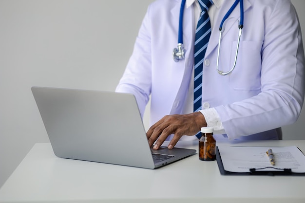 Photo doctor is typing on laptop keyboard filling out patient's visit for medical records treating disease with tinnitus doctor examining a patient doctor concept and treatment by medical professionals