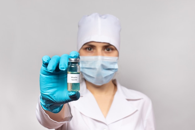 A doctor or lab technician holds a measles vaccine.