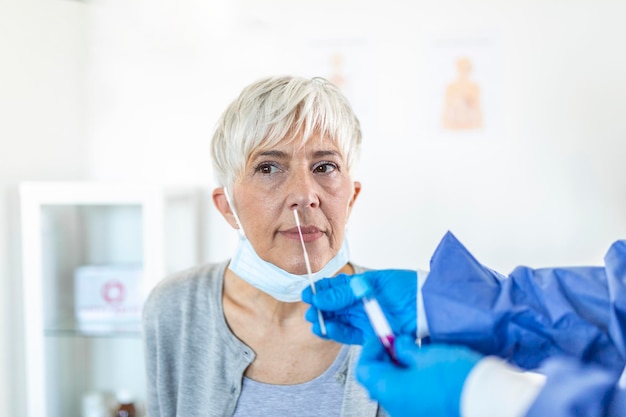 Doctor laboratory assistant in protective suit takes swab from nose of sick patient at hospital. Laboratory tests for coronavirus concept.