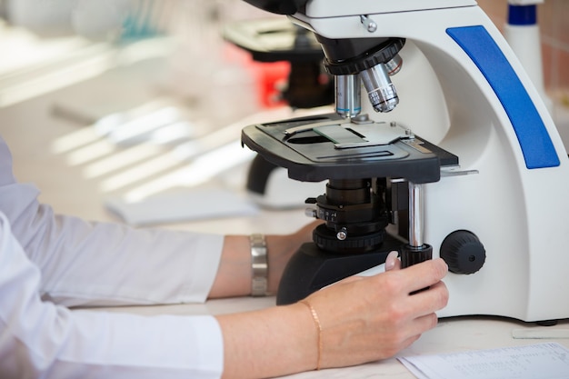 Doctor laboratory worker examines the material under a microscope