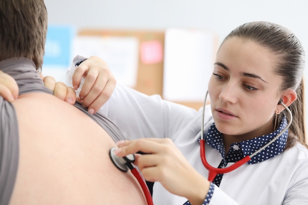 Doctor listening to patient back with stethoscope