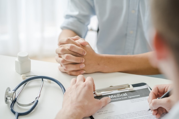 Doctor listening patient explain his symptom and notes to medical record.