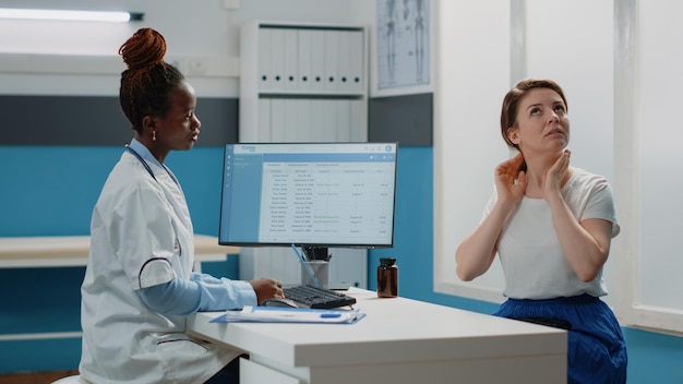 Doctor listening to patient with neck pain and sickness for diagnosis and healthcare treatment in cabinet. Young woman complaining about disease and symptoms to medic at checkup.