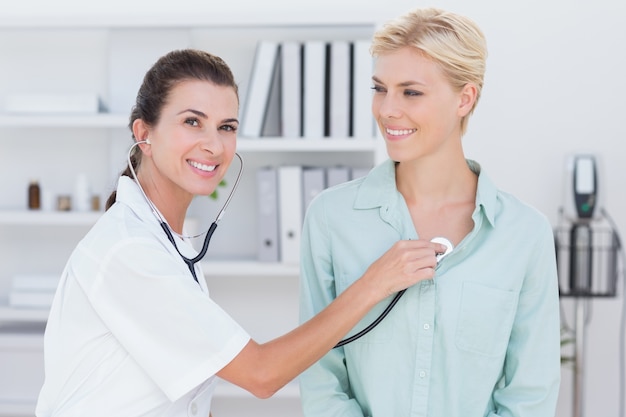 Doctor listening to patients chest with stethoscope