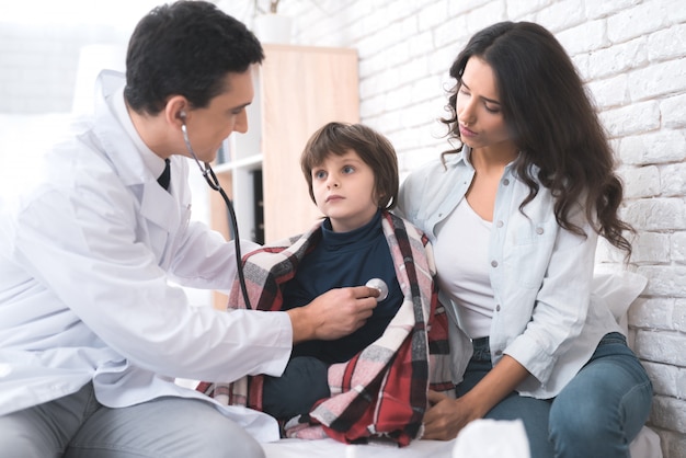 Doctor listens to the heart of a sick boy in a stethoscope.