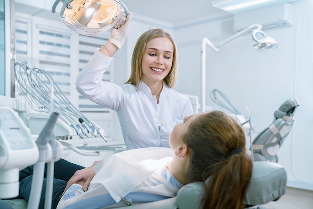 Doctor looking at client lying in dentist chair.