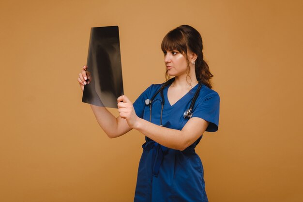 the doctor looks at the topographic X-ray film on a brown background