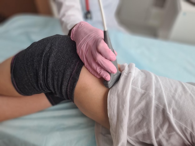 Doctor makes ultrasound of kidneys of liver to patient child in clinic closeup