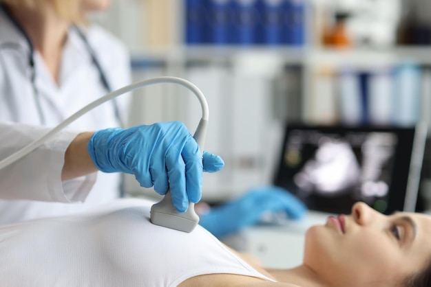 医師は、クリニックで乳房増強の完全な検査の前に女性の乳房超音波治療を行います