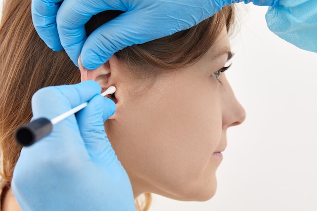 Doctor making ear test with cotton stick to a young woman.