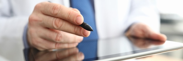 Doctor making notes on graphics tablet close up