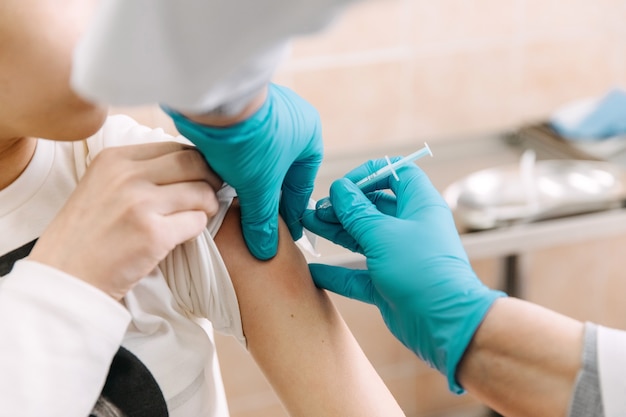 Doctor making a vaccine to a pacient, using a syringe