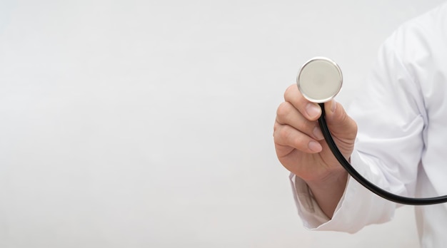 Doctor or male nurse holding up the disc of a stethoscope pointing towards the camera preparing to listen to a patients