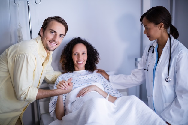 Doctor and man comforting pregnant woman in ward