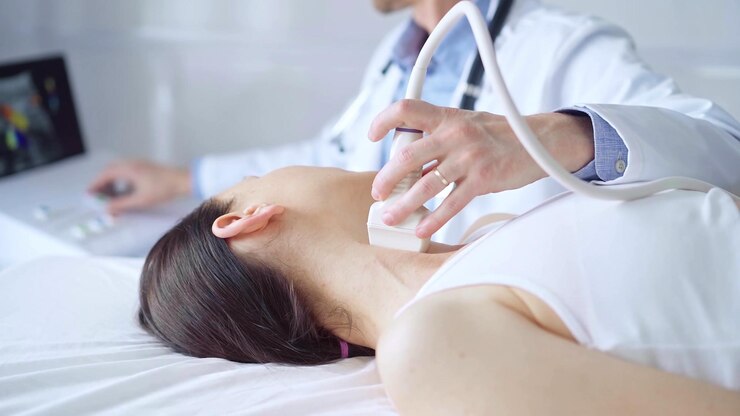 Photo 医師は,医学的検査のために横たわっている女性患者の首に超音波装置を使用しています. 医学と科学