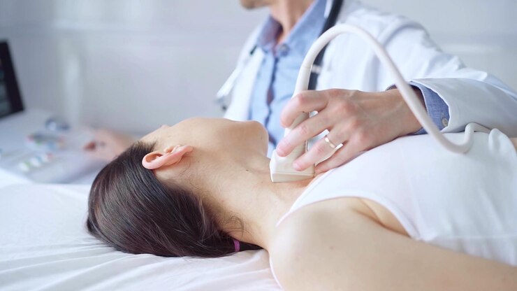 Photo 医師は,医学的検査のために横たわっている女性患者の首に超音波装置を使用しています. 医学と科学